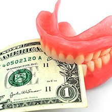 Dentures biting a dollar bill, symbolizing the cost of dentures in Evanston