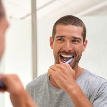 Closeup of man smiling while brushing teeth